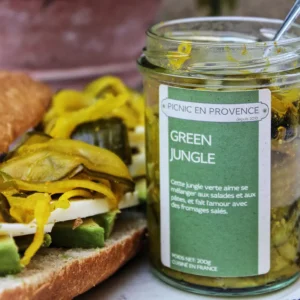 A jar of our homemade Green Jungle next to a sandwich with vegetables and our Green Jungle on top of it.